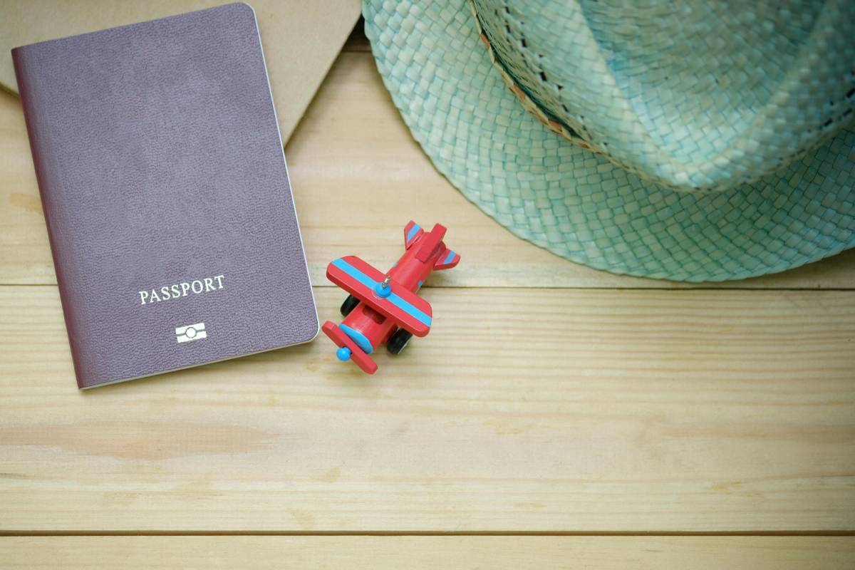 polish passport placed on a wooden table alongwith a toy plane and a light green hat